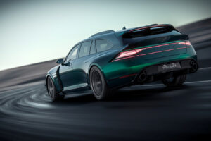 날렵한 녹색 스포츠 왜건 차량이 곡선 도로를 질주하며 뒤에서 바라본 모습입니다. 이 차량은 대담한 라인과 LED 후미등, 뒷면에는 "GENESIS"라는 글자가, 번호판에는 "WINGBACK"이라는 글자가 새겨져 있습니다.